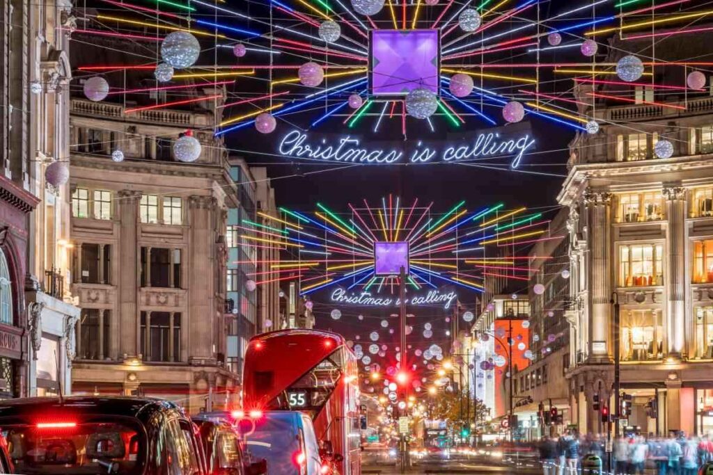 christmas lights on oxford street in london at night with red bus and cars