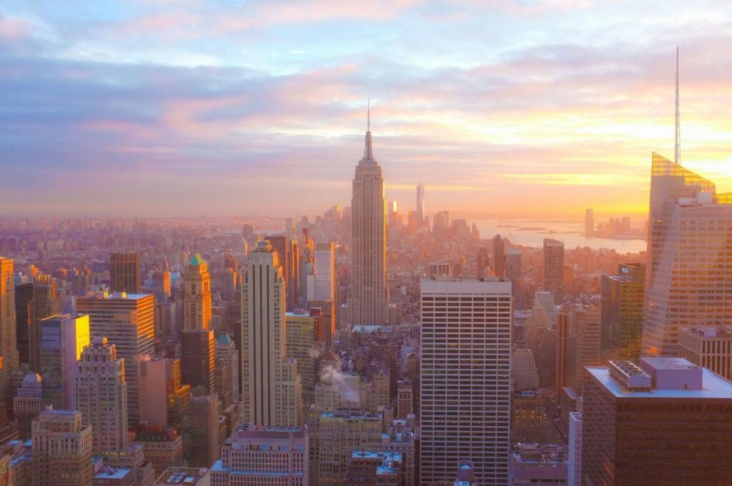 New York City skyline at sunset, featuring Manhattan skyscrapers.