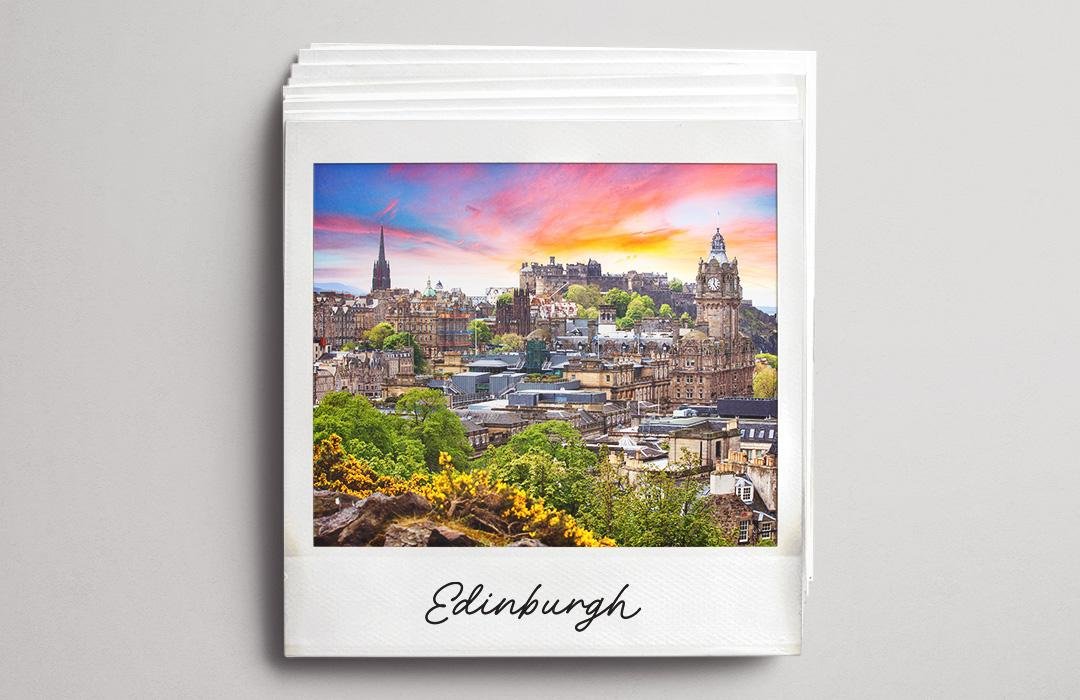 A polaroid photo of the Edinburgh skyline at sunset with a pink and orange sky.