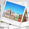 A stack of polaroid photos showing colourful townhouses in a whimsical European town.
